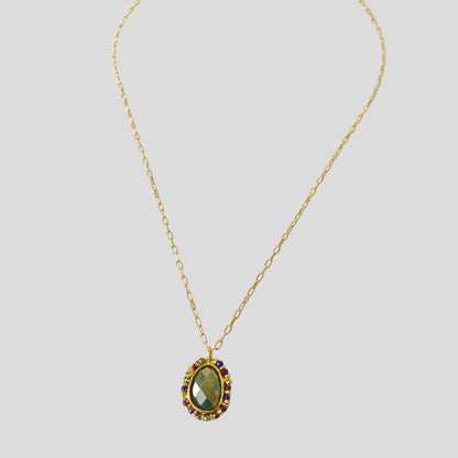 Gold necklace with a green gemstone pendant on a white background
