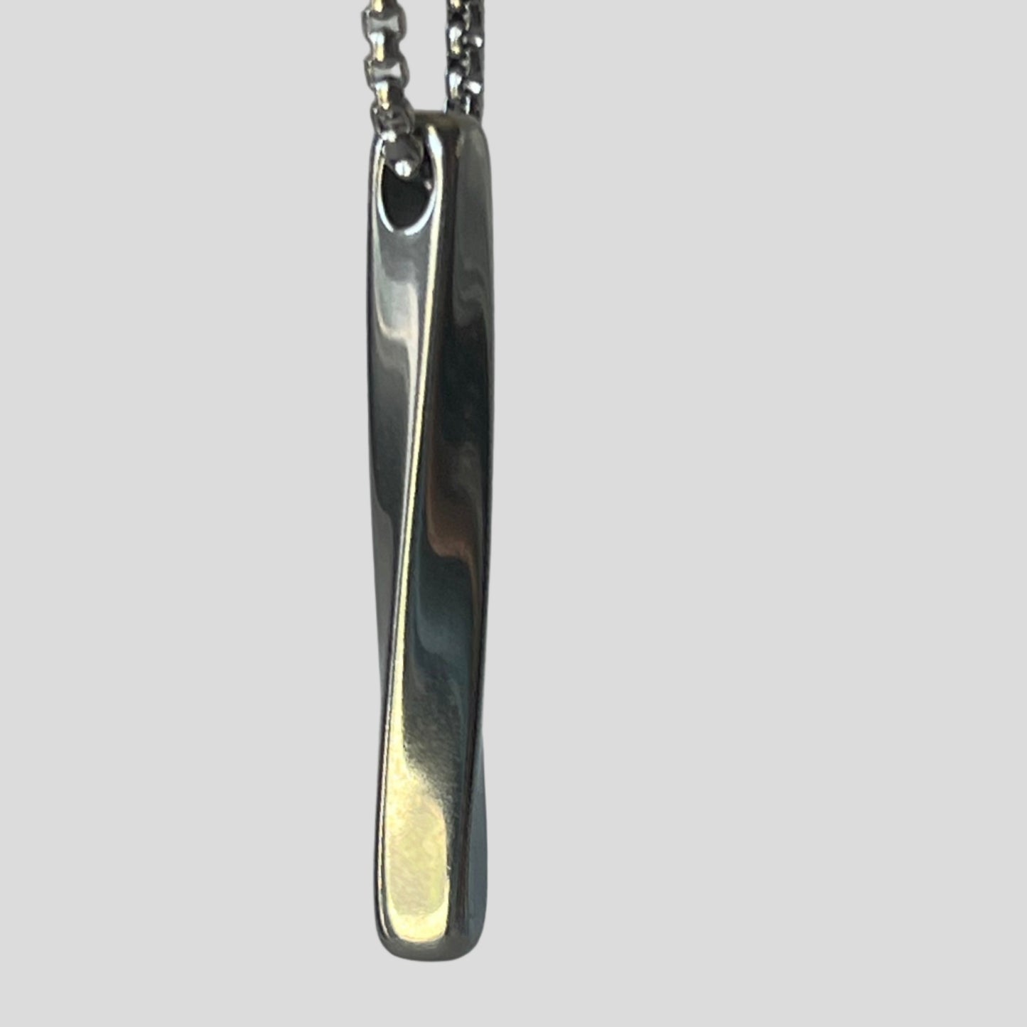 Silver pendant on a chain against a gray background