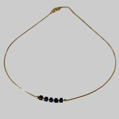 Gold necklace with blue beads on a light gray background