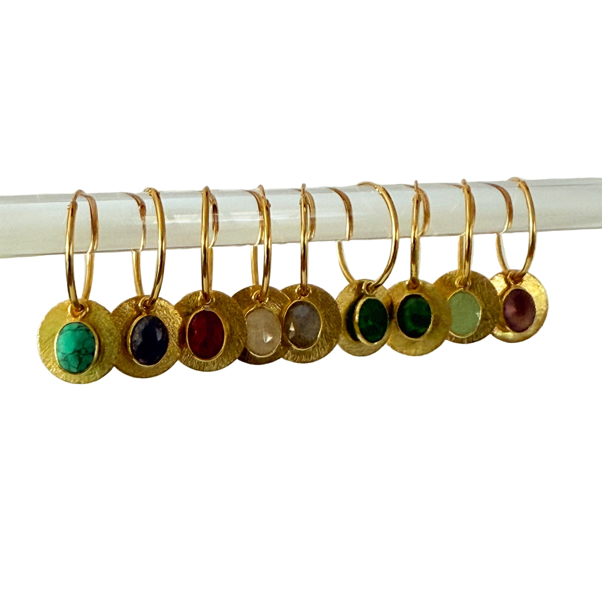 Set of gold earrings with colored gemstones on a white background