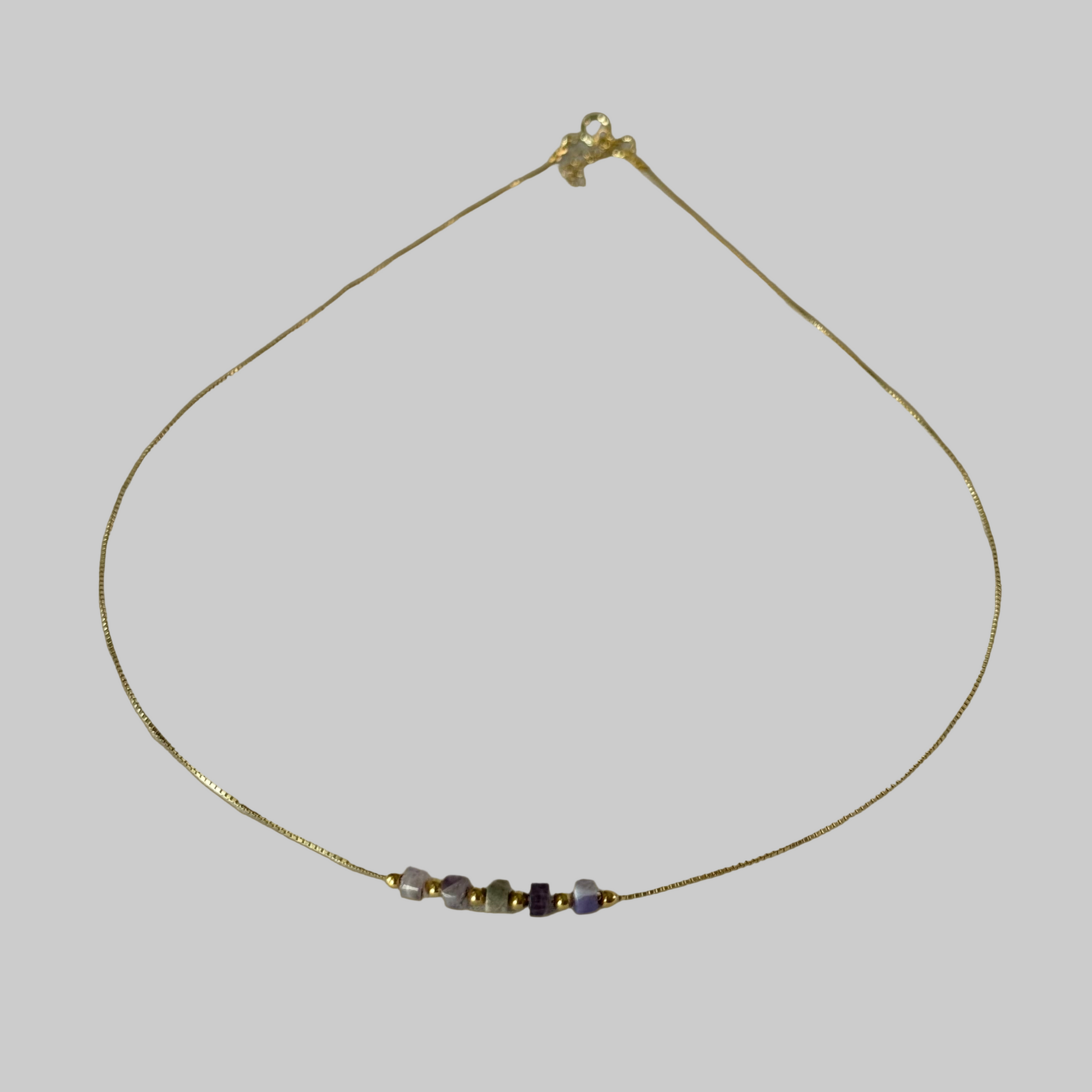 Delicate gold necklace with small beads on a beige background