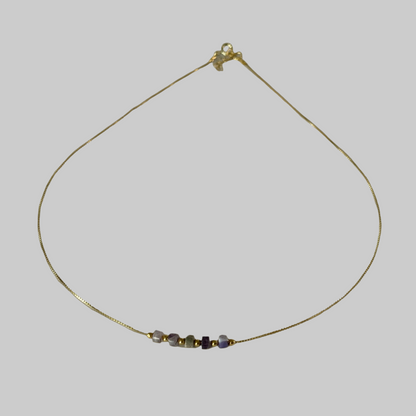 Delicate gold necklace with small beads on a beige background