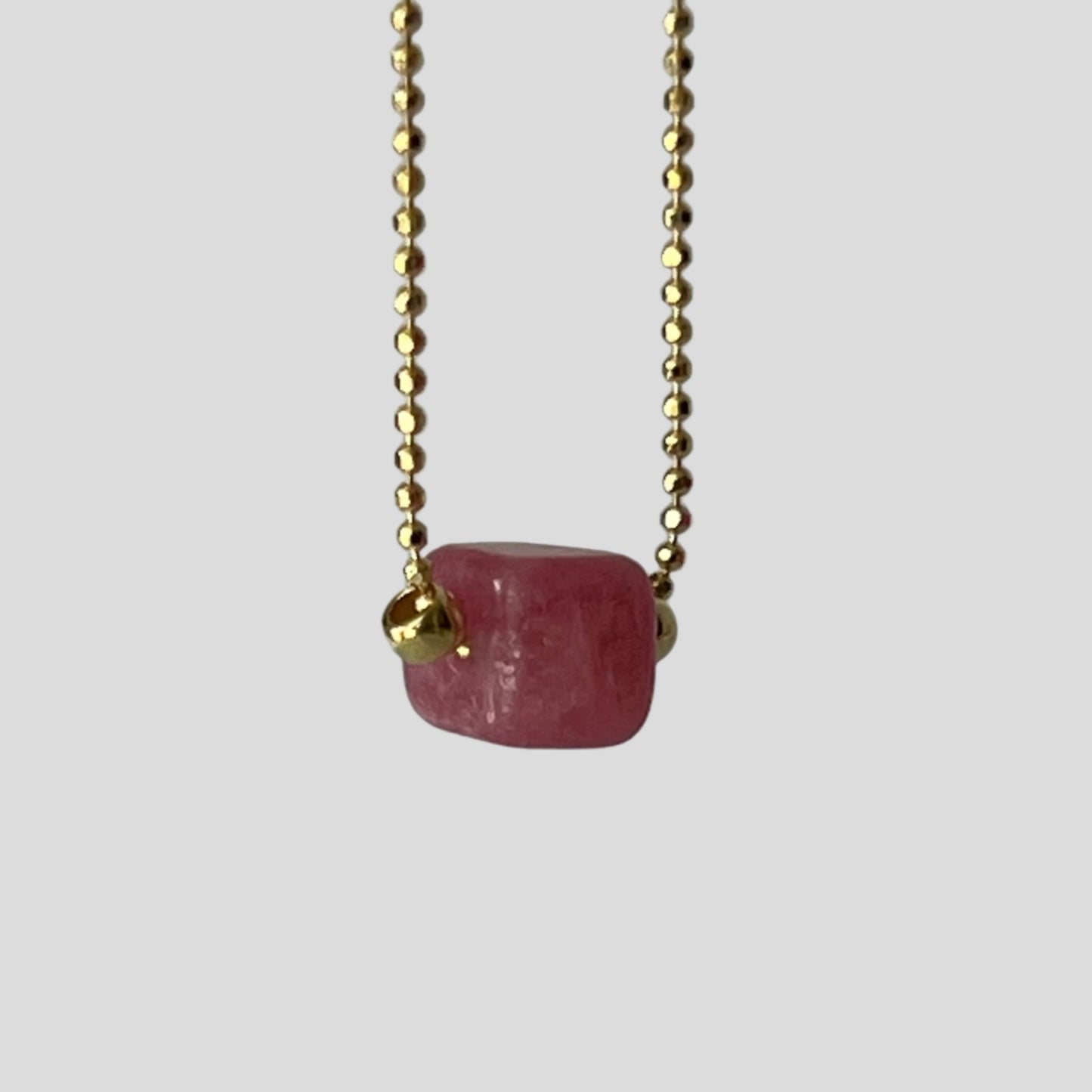 Necklace with a pink gemstone pendant on a blurred background