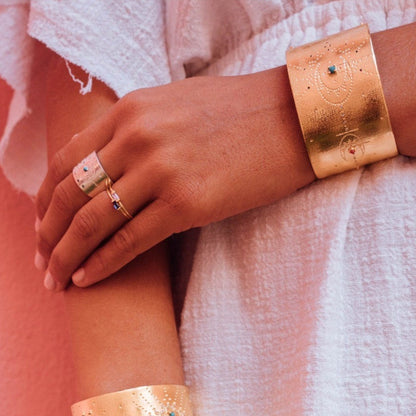 Close-up of a hand wearing two gold bracelets on a white background